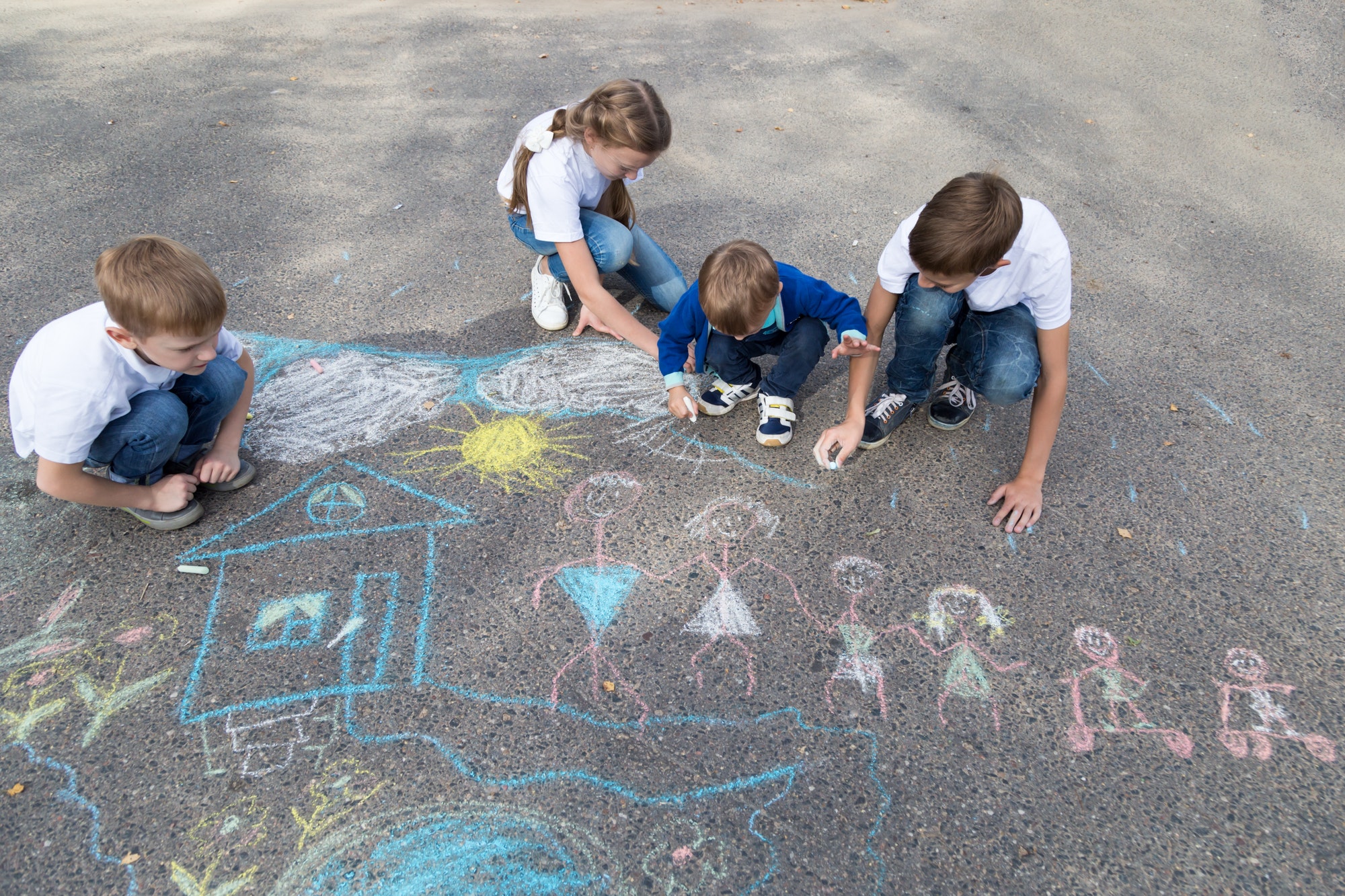 Children draw with crayons on the asphalt